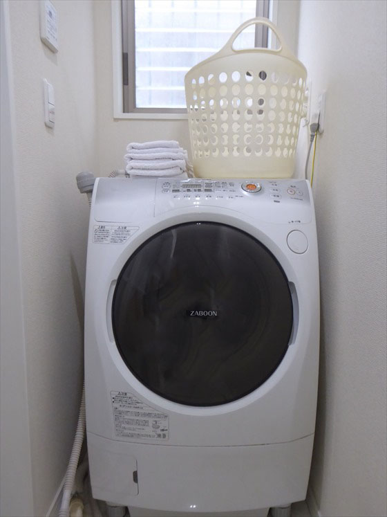 洗濯機の上にタオルと洗濯かごが置いてある様子