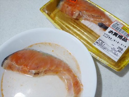 皿に入った鮭と日本酒。隣にパックに入ったままの塩鮭