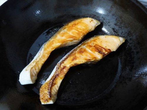 フライパンで塩鮭を2切れ焼いている様子