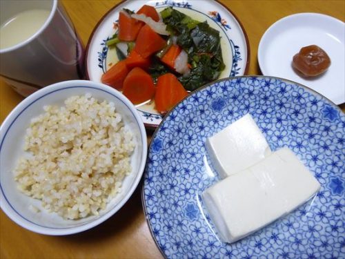 皿に取り分けた湯豆腐や煮物、玄米と小皿に梅干し