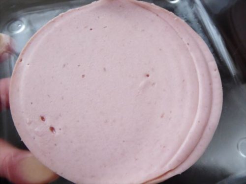 大豆ミートハムを至近距離で撮影した写真、ピンクで丸く、所々に穴が開いている