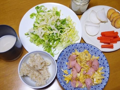 皿に盛った魚肉ソーセージと卵炒めに千切りキャベツと玄米、皿に盛ったぬか漬けとピクルス