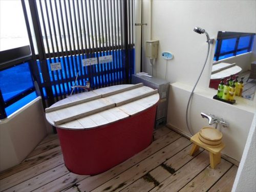 テラスにある客室露天風呂、赤い浴槽に木の蓋がされている