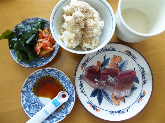 切った刺身、小皿にキムチとワカメ、茶碗には玄米とすりごま