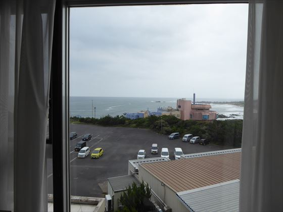 部屋の窓からの景色、駐車場の車と海が見える