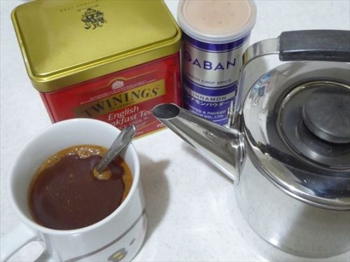 キッチンに並ぶ紅茶の缶、シナモンの容器、急須、マグに入れた紅茶